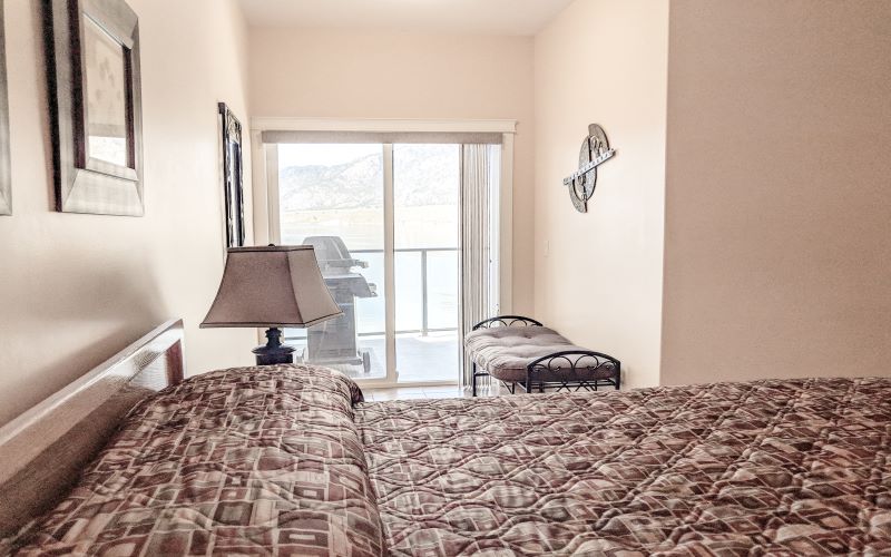 Bedroom with lake-facing balcony access in the Deluxe Waterfront 2 Bedroom suite